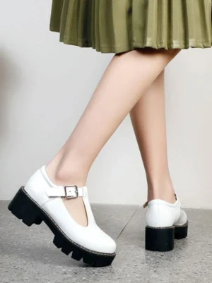 White patent leather T-strap lolita platform pumps rear side view with adjustable buckle and chunky lug sole, styled with green pleated mini skirt