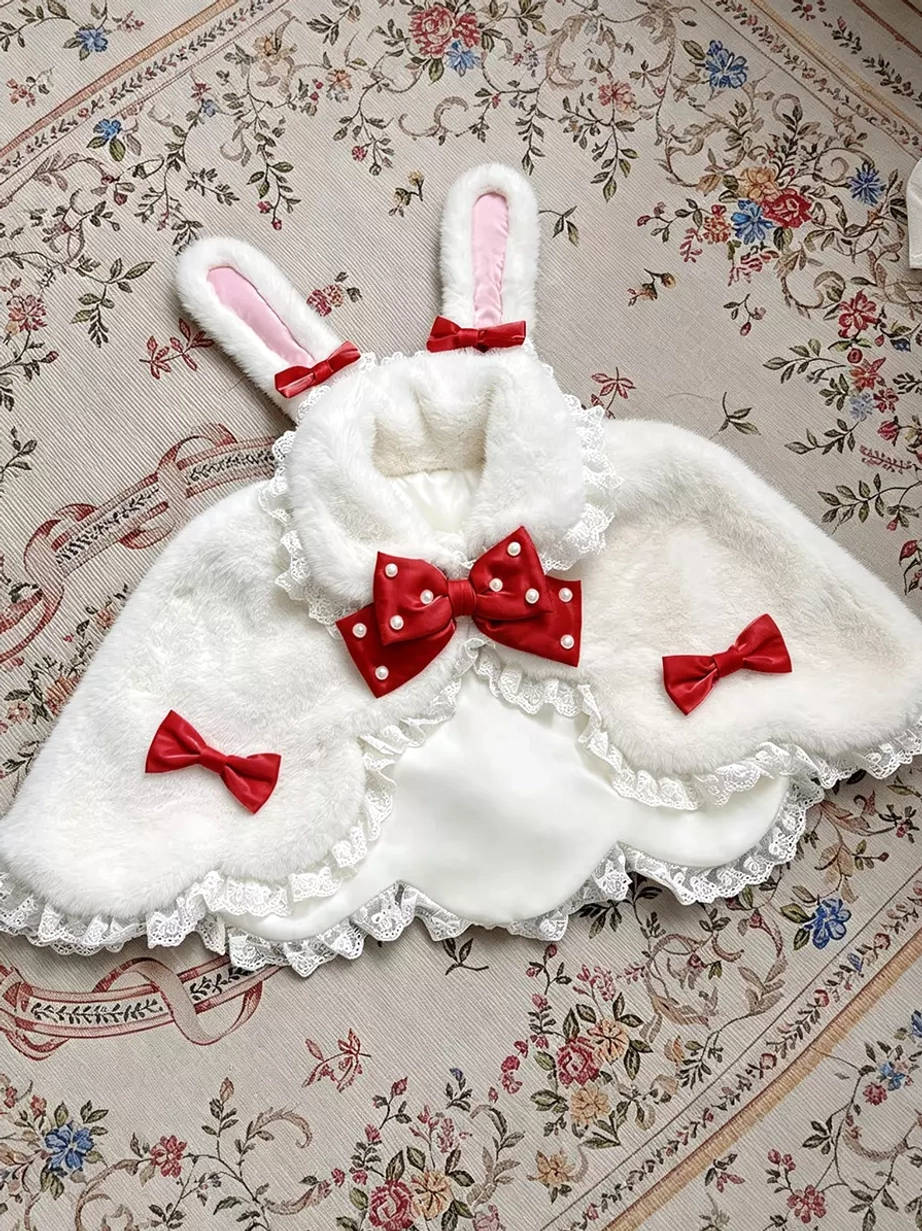 White fuzzy lolita bunny ear plush shawl with red polka-dot bows and ivory lace hem, flat lay display on vintage textured fabric