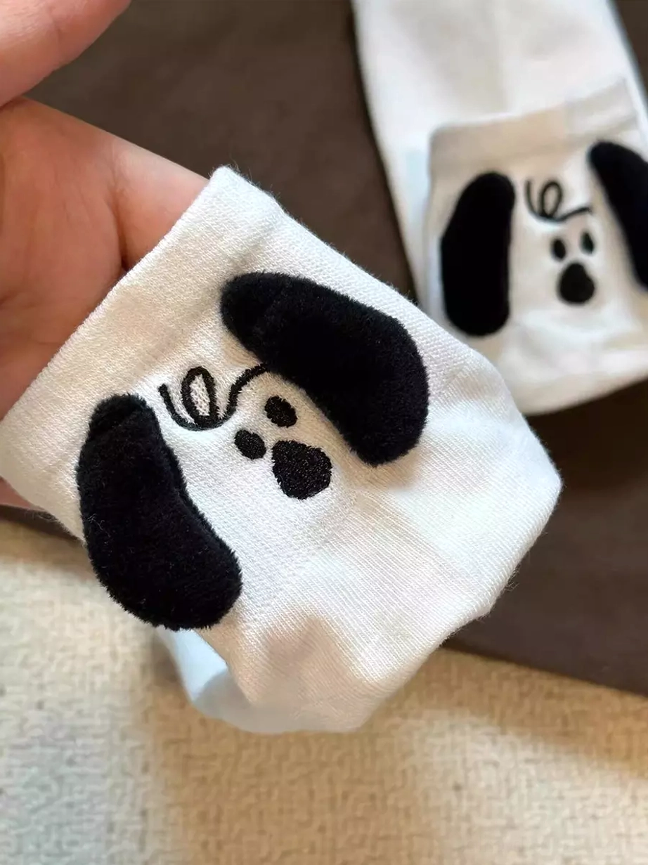 White cartoon puppy themed lolita socks flat lay showing embroidered facial patterns and flocked ears, kawaii hosiery design detail