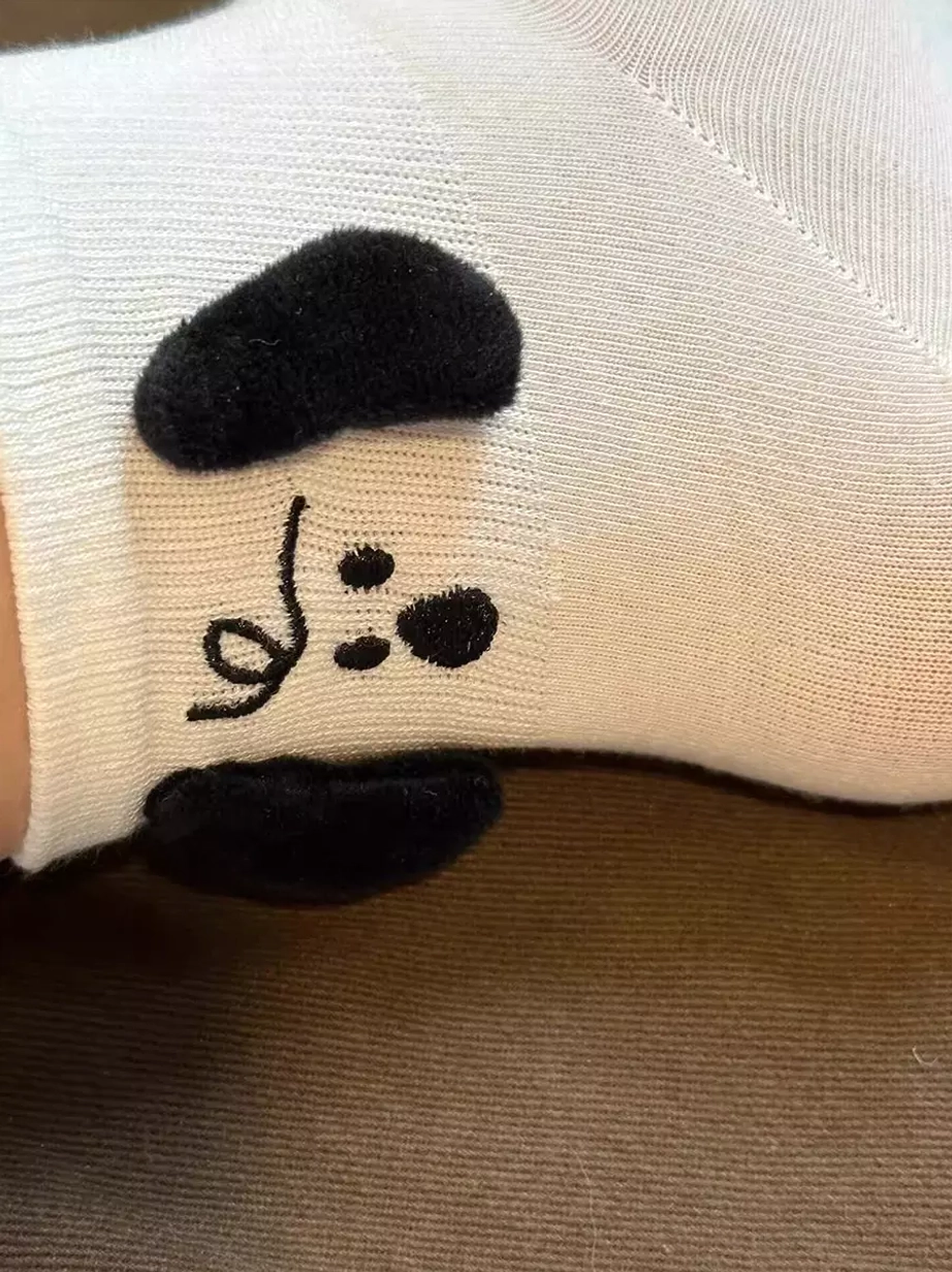 Close-up side view of white 3D puppy plush socks showing ribbed knit fabric texture, dimensional plush dog ears and embroidered details