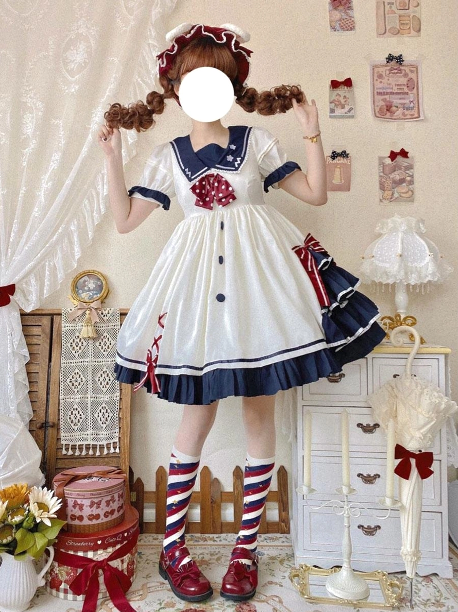 white sailor sweet lolita dress with navy collar and red polka dot bow front view on model wearing vintage indoor boutique setting