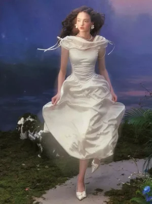 White satin cowl neck fairy lolita midi dress with drawstring shoulder straps and draped neckline, full-body view against twilight waterside setting, displaying the elegant sleeveless design and flowing skirt silhouette perfect for sweet lolita fashion