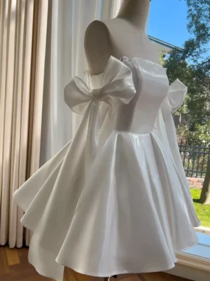 White sweet lolita dress with oversized satin bows on shoulders, square neckline, and flared a-line mini skirt, front three-quarter view