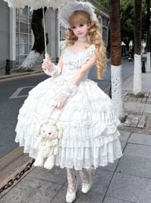 White off-shoulder sweet lolita ball gown with tiered lace ruffles and matching bonnet worn outdoors with blonde model