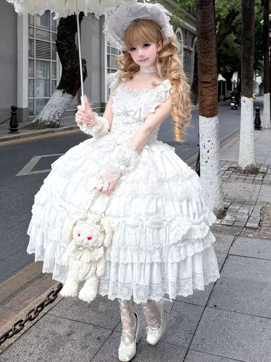 White off-shoulder sweet lolita ball gown with tiered lace ruffles and matching bonnet worn outdoors with blonde model