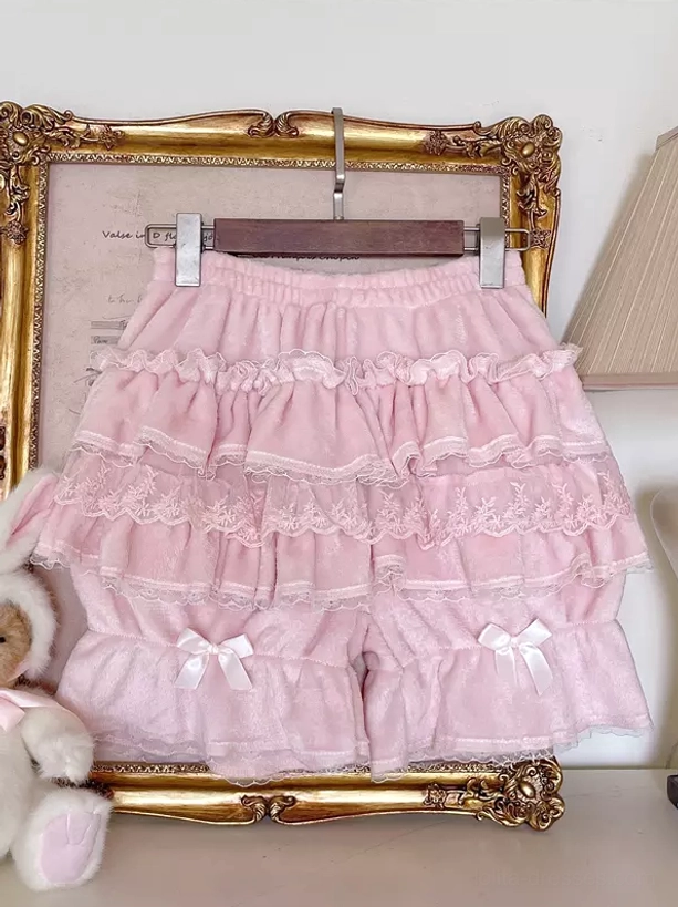 White Sweet Lolita bloomers flat display view with lace ruffled layers, velvet fabric, and small decorative hem bow against vintage indoor background