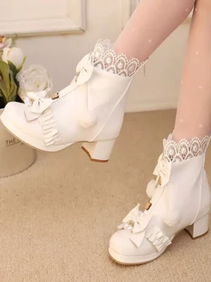 White Sweet Lolita heeled boots with floral indoor backdrop, front double on-foot view featuring lace-trimmed socks, decorative bow embellishments, pom-pom and ruffle trims