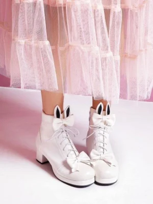 White sweet lolita ankle boots with bunny ear bows and round block heel, featuring lace-up front and side zipper, displayed on pair with tulle skirt background