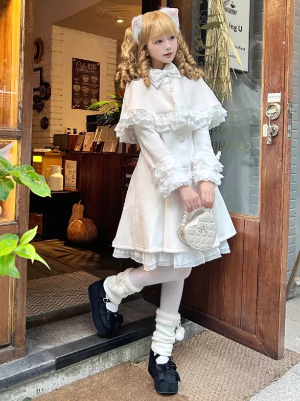 White sweet lolita cape coat full body front view with removable lace cape ruffled cuffs and collar worn at cafe entrance