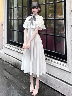 White sweet lolita midi dress with mesh bows and black bow necktie front view on female model wearing vintage street shop exterior backdrop