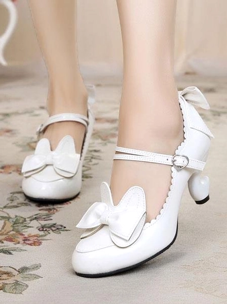 White lolita cat-ear bow heels with scalloped shoe edges and delicate details on indoor carpet, side close-up showing round toe silhouette