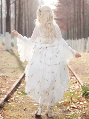 Back view of white lolita JSK dress showcasing large decorative back bow, flared ruffled sleeves, and wheat print design in forest backdrop