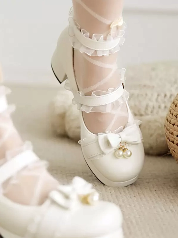 White Sweet Lolita Mary Jane pumps with pearl charm bow and ruffled ankle straps, top-down overhead shot on carpeted floor showing detailed shoe design
