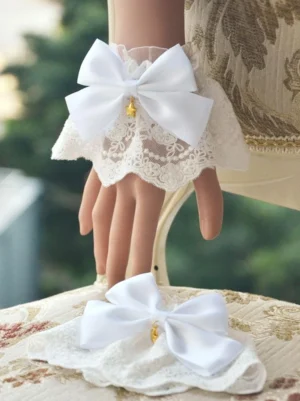 white sweet lolita wrist cuffs with ruffled lace trim and matching satin bow featuring gold star charm pendant worn on mannequin hand floral chair background