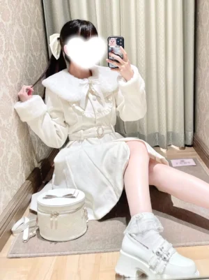 white sweet lolita winter coat sitting perspective with matching handbag platform shoes and hair bow accessory