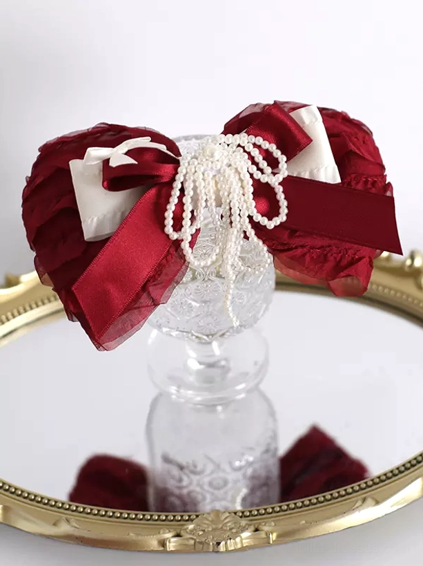 Flat lay view of wine red lolita bow hair clip headdress displayed on gold-rimmed mirror tray with reflection showing pearl tassel details