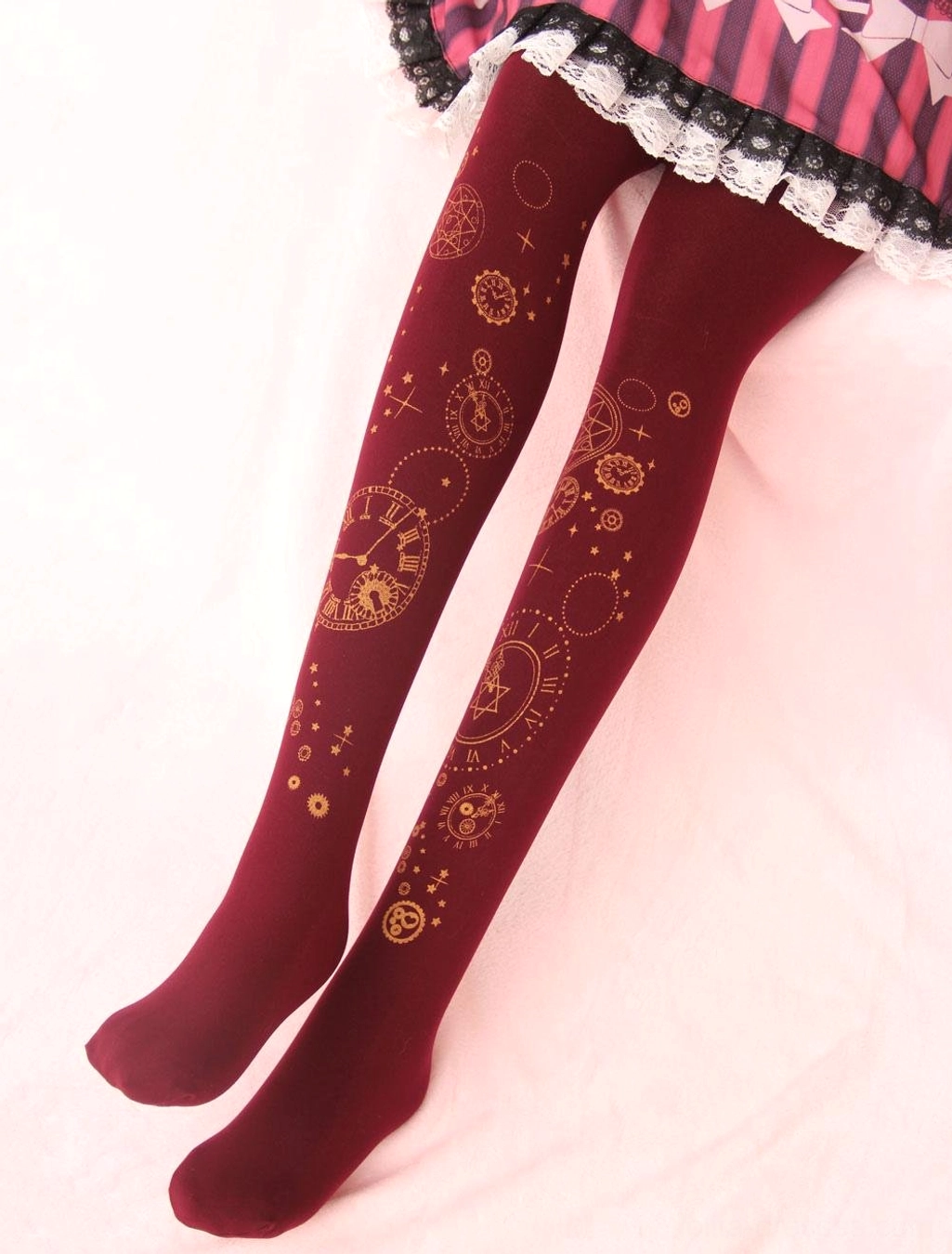 Wine red velvet lolita pantyhose with luxurious gold foil clock and gear hot stamping, worn with frilled lolita skirt on pink plush background - elegant presentation