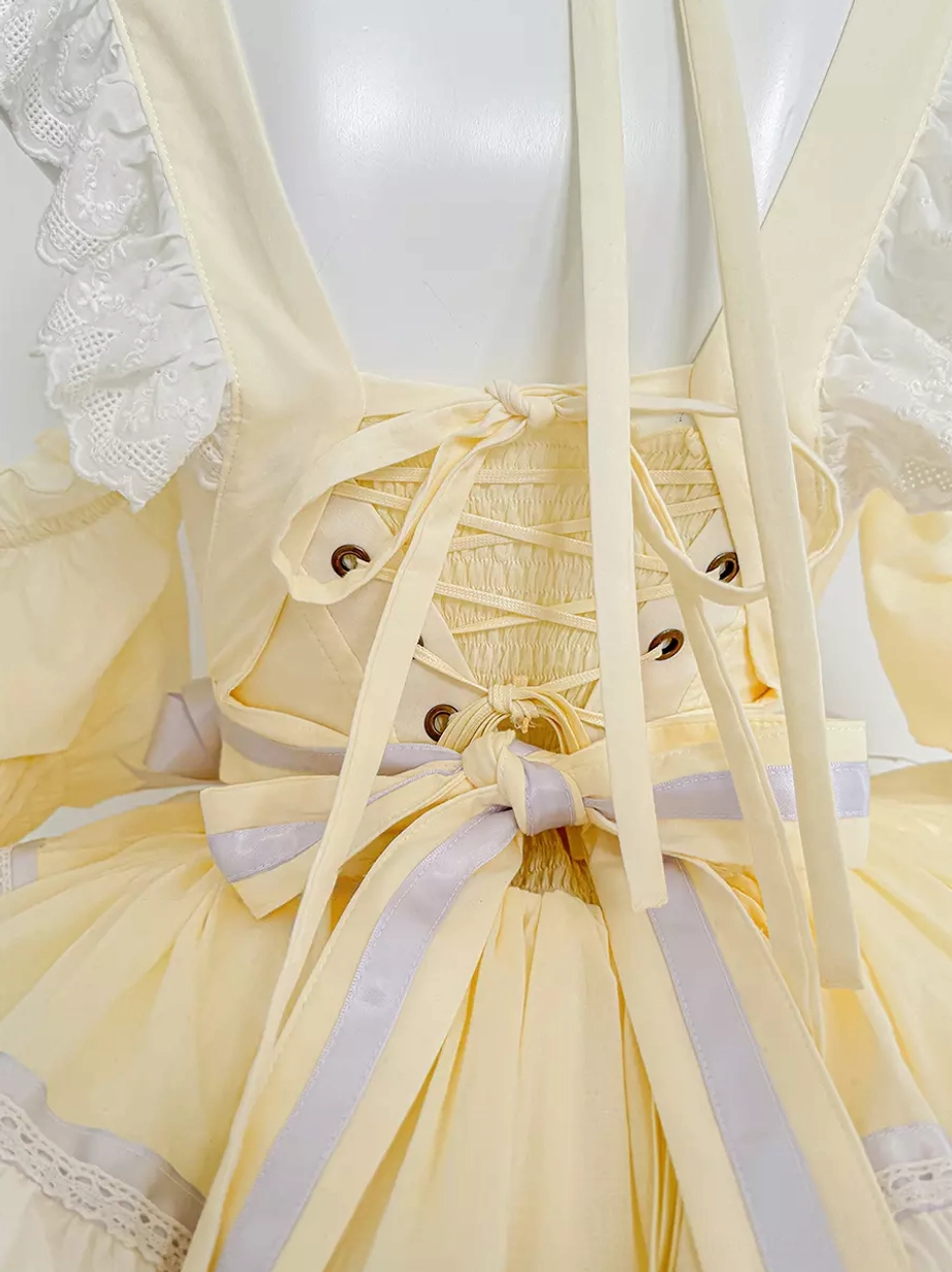 Close-up of yellow lolita dress back detail showing lace shoulder straps, corset lace-up closure, and purple sash bow decoration with precision construction